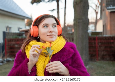happy girl in bright clothes and headphones with rose flower
