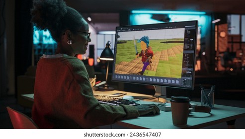 Portrait of Black Female Video Game Designer Creating Metaverse and Design Video Game Character in Creative Office at Night. Focused Woman Working on a New 3D Level on Her Desktop Computer