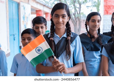 Group of happy village children in school uniform celebrating independence day with Indian flag in hand - concept of independence, republic day, patriotism and freedom.