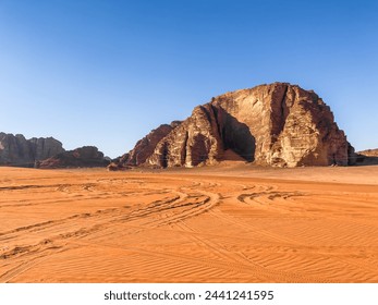 آثار إطارات السيارات والشاحنات على رمال الصحراء أمام مشهد مذهل