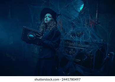 Fabulous Halloween. Mlada vještica čarobnica baci čini čarobnim štapićem. Pejzaž starog zamka obavijenog paučinom. Fantazija.