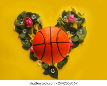 Basket classico su foglia verde a forma di cuore e rose rosse e pietre preziose, sfondo di superficie di colore giallo. Concetto di amore per lo sport. Disposizione piatta.