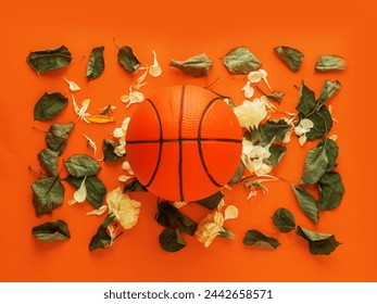 Basket classico su superficie color arancione con foglia di rosa verde e petali, concetto di sport d'amore. Disteso in piano.