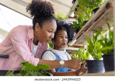 African mother and daughter is choosing tropical fern and ornamental plants from the local garden center nursery during summer for weekend gardening and outdoor usage