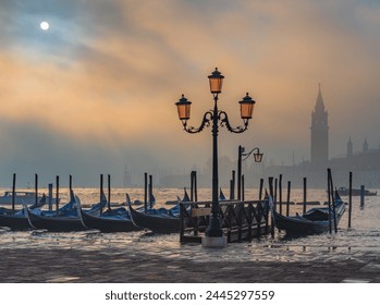 Gondolas in Venice at sunrise in morning fog. Veneto, Italy.