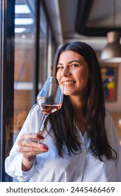 One young woman or girl is holding glass of wine and drinking wine in winery while enjoying and smiling