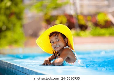 Klengt Meedchen an der Schwämm. Kand léiert schwammen am Outdoor Pool vum tropesche Resort. Waasser Spaass fir Puppelcher a Kleeder. Rees mat Kanner. Summer Famill Vakanz. Plage Vakanz mat jonke Kand.