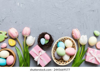 Cornice pasquale con uova, scatola regalo e tulipano su sfondo colorato. Il concetto minimale. Composizione di Buona Pasqua vista dall'alto. Biglietto con uno spazio di copia del posto per il testo.