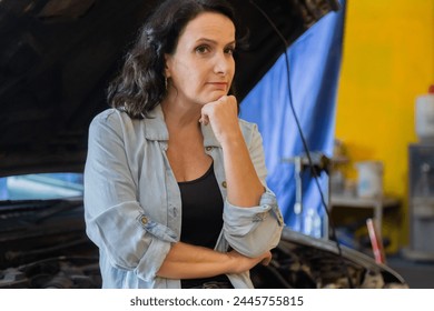 Middle-aged small business entrepreneur female standing arm crossed in front auto repair service shop,   portrait of garage owner woman happy start-up business, automobile technician worker lifestyle