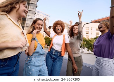 Happy Young girl friends dancing for celebrate success. Smiling female Group of only women having fun together outdoors. Cheerful community of students university. Lifestyle of multicultural people