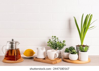 Set Barangan Majlis Teh di Atas Meja Batu Dapur dengan Tanaman Berpasu Dinding Bata Putih. Ruang salinan. Latar belakang dapur.