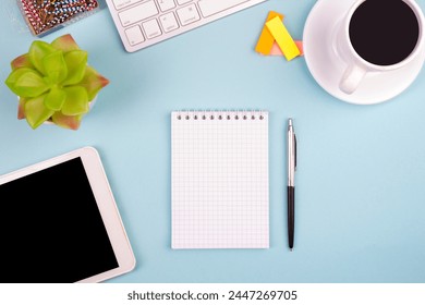 Tablet, calculator, phone, pen and a cup of coffee, lot of things on a blue background. Top view with copy space
