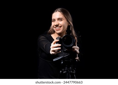 Porträt einer Fotografin mit moderner Kamera auf Stativ vor schwarzem Hintergrund