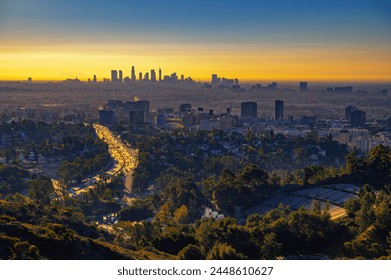 Centar Hollywooda u izlasku sunca sa horizontom Los Anđelesa u pozadini i saobraćajem na autoputu US-101 u prvom planu.