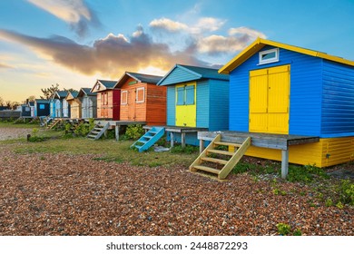 กระท่อมชายหาดสีสันสดใสบนชายหาดกรวดหินยามพระอาทิตย์ขึ้น วิทสเตเบิล เคนต์ อังกฤษ สหราชอาณาจักร ยุโรป