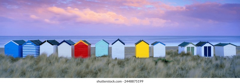 กระท่อมชายหาดสีสันสดใสและเนินทรายยามพระอาทิตย์ตกดิน เซาท์โวลด์ ซัฟโฟล์ค อังกฤษ สหราชอาณาจักร ยุโรป