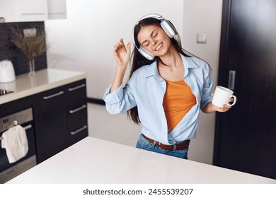 Woman Enjoying Morning Coffee and Music in the Kitchen with Headphones on