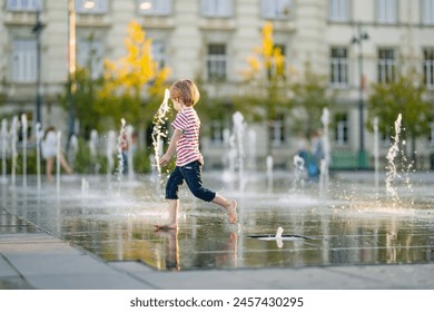 Lindo niño divirtiéndose con agua en una fuente de la ciudad. Niño jugando juegos acuáticos al aire libre en un día caluroso. Actividades de verano para niños pequeños.