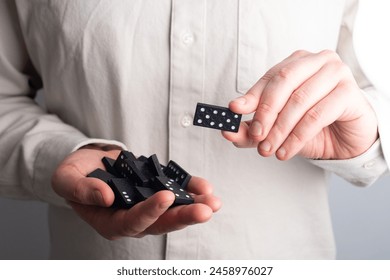 Domino nero nelle mani di un uomo. Concetto di effetto domino. Concetto di business, rischio, gestione e finanza