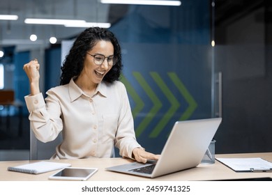 Hispanesch Geschäftsfra feiert Victoire, Mataarbechterin mat gekrauselten Hoer am Büro liest gutt Neiegkeeten, benotzt Laptop op der Aarbecht am Büro, hält d'Hand an d'Luucht a freet sech iwwer e glécklecht Triumph