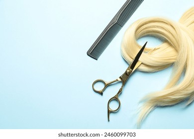 Professional hairdresser scissors and comb with blonde hair strand on light blue background, flat lay. Space for text