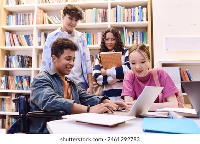 Retrato de um adolescente sorridente usando um laptop na biblioteca da escola com um grupo diversificado de alunos trabalhando juntos em um projeto