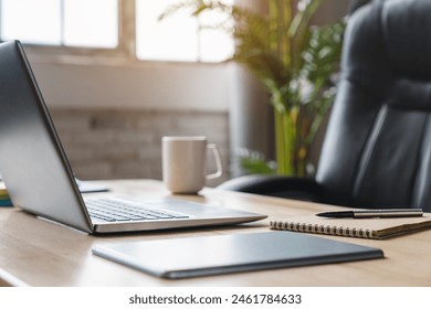 Imagem da mesa de um funcionário de escritório com laptop, documentos e bloco de notas. Computador, livros, vaso de planta, cadeira e materiais de escritório sobre uma mesa de madeira. Local de trabalho vazio.