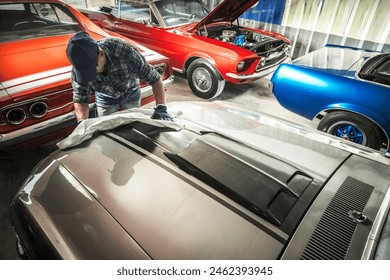 Mann wäscht Oldtimer-Motorhaube in der Garage. Thema klassische Fahrzeuge