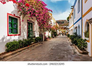 Straße mit blühenden Blumen in Puerto de Mogan, Gran Canaria, Spanien. Beliebter Urlaubsort für Touristen und Einheimische auf der Insel. Puerto de Mogan mit vielen Bougainvillea-Blüten, Kanarische Inseln.