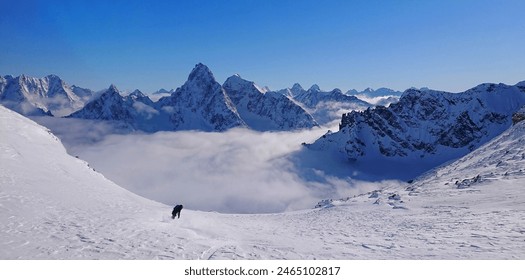Extrem-Freeride-Snowboarder fährt den schneebedeckten Berg hinunter und in Richtung des wolkigen Tals in British Columbia. Junge Frau im Aktivurlaub fährt mit dem Snowboard einen atemberaubenden Berg in den kanadischen Rocky Mountains hinunter.
