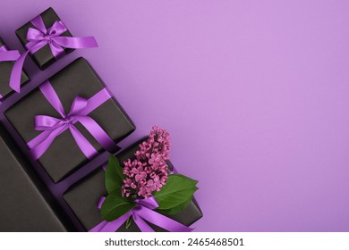 Set of black gift boxes with lilac flowers and violet ribbons. Horizontal, space for your text.