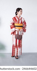 Corps entier d'une jolie femme japonaise portant un yukata rouge. Fond blanc.