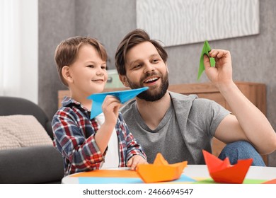Padre e hijo felices jugando con aviones de papel en casa