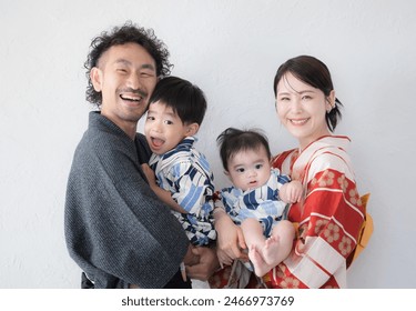 Une famille souriante, prête à être photographiée, en yukata. La moitié supérieure du corps a été prise sur un fond blanc.