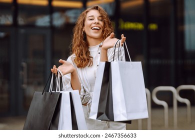 Stylowa kobieta z torbami na zakupy przechadza się ulicami miasta. Konsumpcjonizm, moda, zakupy, koncepcja stylu życia.