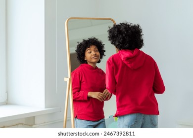 自分を愛してください。美しく若い笑顔のアフリカ系アメリカ人女性が鏡に映った自分の姿を楽しんで踊っています。黒人女性が鏡を見て自信に満ちて幸せそうにしています。自己愛のコンセプト
