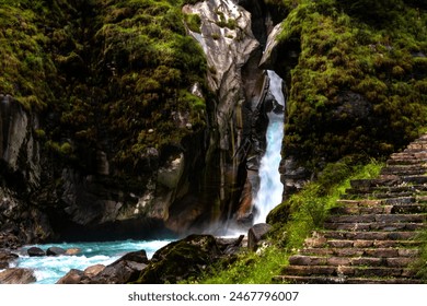 Cascada printre munții Himalaya cu pădure verde și un râu plin de stânci.