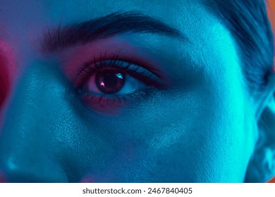 Close-up photo of woman's eye, highlighting well-defined eyebrow, long eyelashes, and smooth skin in neon light. Concept of beauty and care, cosmetology, wellness, spa treatments. Ad