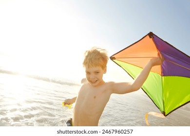 Boy, ocean and kite on beach with fun, adventure and playing in sunshine for summer holiday. Excited child or happy kid with game for fantasy, imagination and wind for travel or vacation in sea water