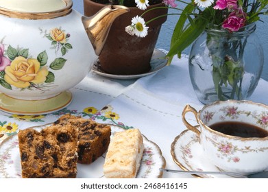 Popołudniowa herbata w ogrodzie, ciasta z porcelany vintage i świeże kwiaty wiejskie