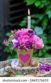 aranjament floral romantic cu o lumânare, trandafiri roz Leonardo da Vinci, flori de violă și caprifoi în ghiveci de turbă cu ornament de inimă