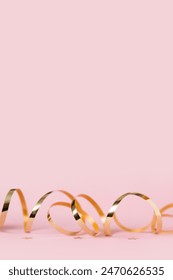 Semplice sfondo rosa con nastro a spirale dorato. Biglietto di auguri per le feste. Buone feste. Minimo, disposizione piatta, spazio per la copia. Mockup. Verticale