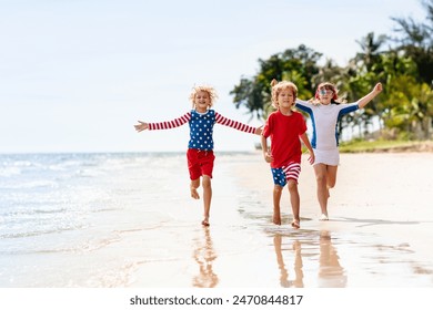Kanner lafe mam USA Fändel op sonneger Plage. 4. Juli Feier. American Famill Spaass op Onofhängegkeet Day Weekend. Patriotesch Kanner feieren US Vakanz. Jong a Meedchen mat Symboler vun Amerika.
