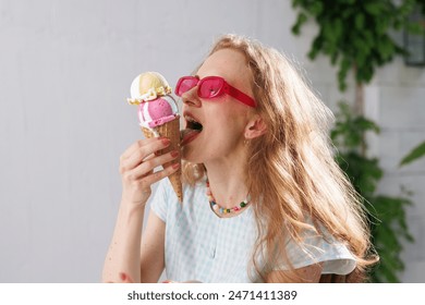 Mädchen isst Eiskugeln im heißen Sommer, entkommt der Hitze Mädchen mit rosa Brille isst Eiskugeln im heißen Sommer, entkommt der Hitze