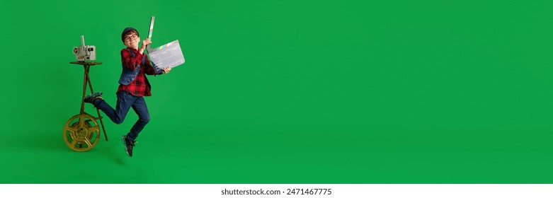 Banner. Dječak odjeven kao filmski redatelj, držeći klapnu, skače od uzbuđenja na zelenoj pozadini studija. Koncept dječjih snova, buduća karijera, zanimanje, igre, fantazija. Oglas
