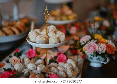 Włoskie ciasteczka weselne na eleganckim, kolorowym stole z deserami w formie bufetu ze scones, makaronikami, słodyczami, ciasteczkami, kwiatami w filiżance na przyjęcie weselne, rocznicę dziecka, przyjęcie herbaciane i lunch