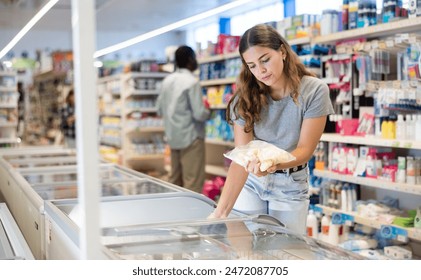 Jonk Fra steet am Frigo, wielt gefruer Komfort Iessen am Supermarché.