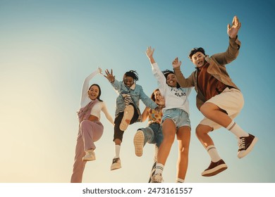 A group of cheerful young friends jumping together in joy, celebrating friendship and having fun outdoors on a sunny day.