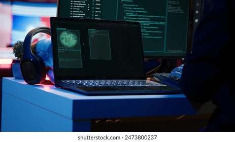 후드를 쓴 스크립트 키디가 가방에서 노트북을 꺼내 DDoS 공격을 시작할 준비를 하고 있습니다. 컴퓨터 책상에 앉아 가방에서 노트북을 꺼내 맬웨어 스크립트 작업을 시작하는 사기꾼의 클로즈업 샷, 카메라 A