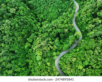 Aerial view of a road in the middle of the forest , road curve construction up to mountain